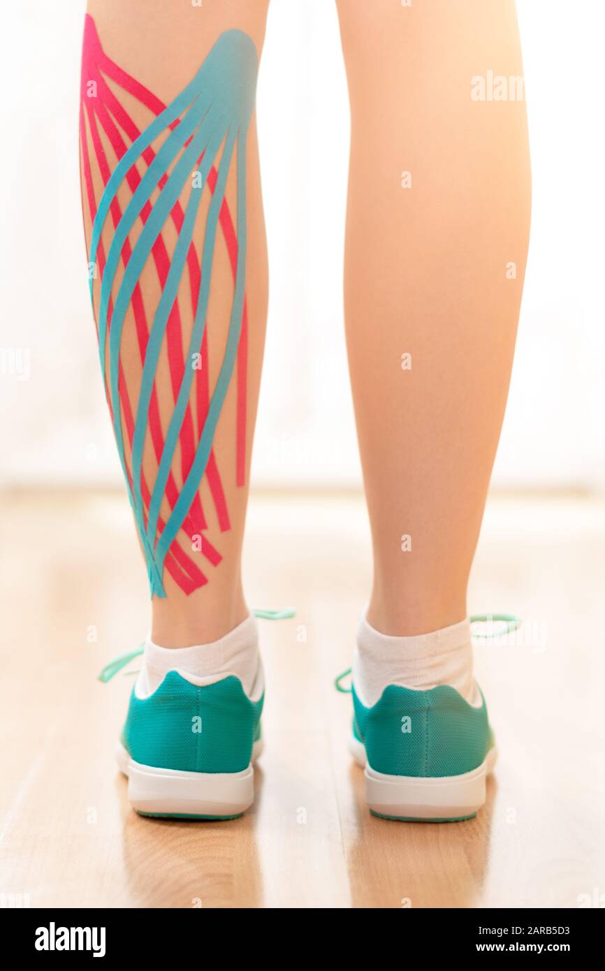 Female patient with kinesio tape on her calf standing in front of a window,  rear view leg close up. Kinesiology, physical therapy, rehabilitation conc  Stock Photo - Alamy