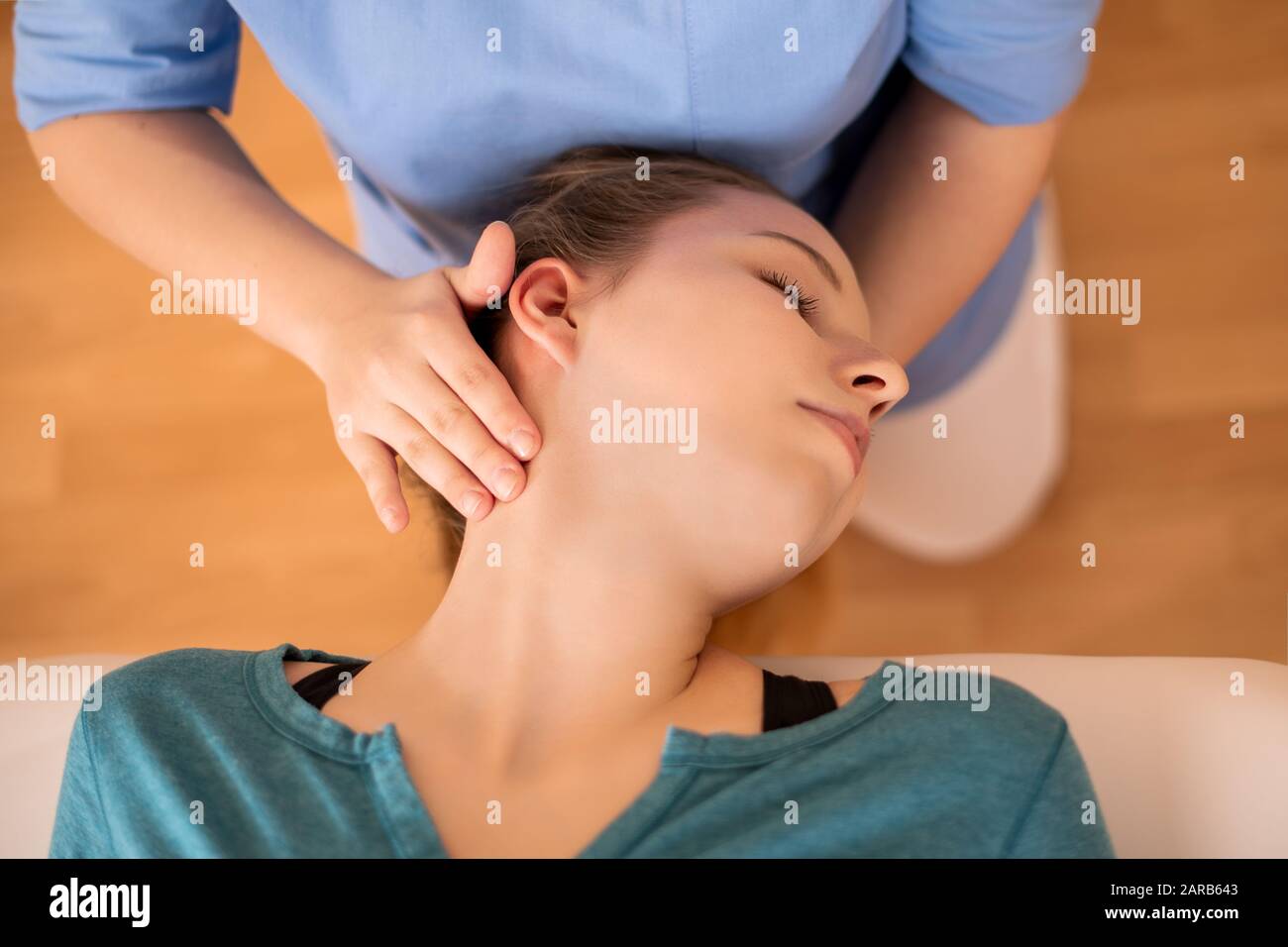 Female physiotherapist or a chiropractor adjusting patients neck. Physiotherapy, rehabilitation concept. Top view close up. Stock Photo