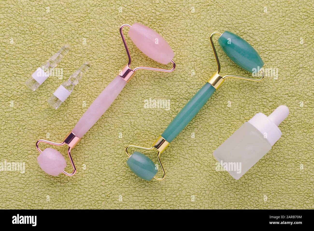 jade and rose quartz facial roller with face serum in ampoules and bottle, above Stock Photo