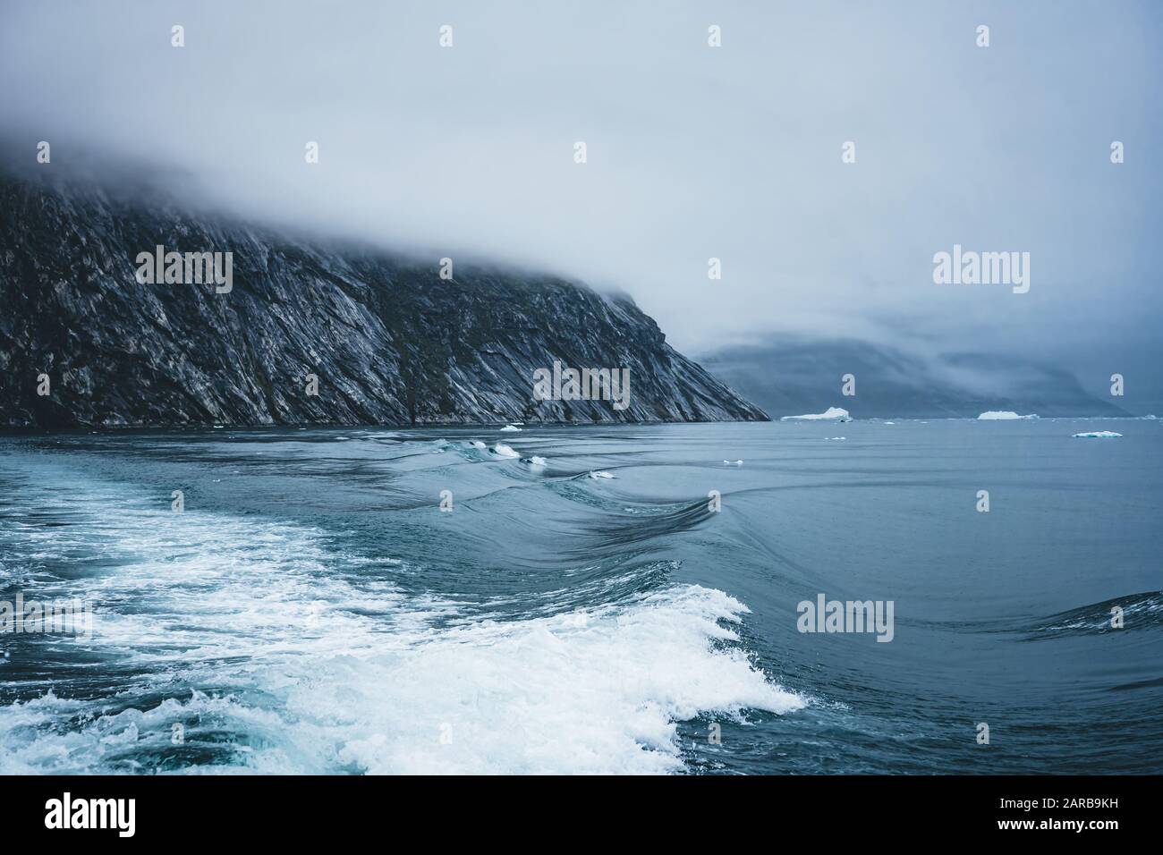 Waves crashing at the shore on an overcast day in the arctic circle in Greenland. Powerful ocean waves breaking.Wave breaks on a shallow bank. Natural Stock Photo