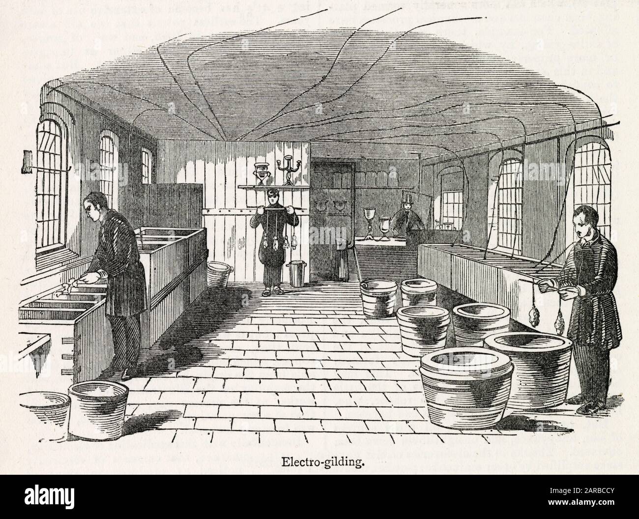 The silver deposit room at Elkington's Electro-plate Factory, Birmingham. The objects to be plated are connected to an electrical cable (routed across the ceiling) and then immersed into tanks containing a solution of silver and potassium cyanide salts.     Date: 1844 Stock Photo