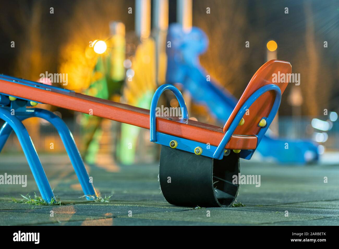 Seesaw swing in preschool yard with soft rubber flooring at night. Stock Photo