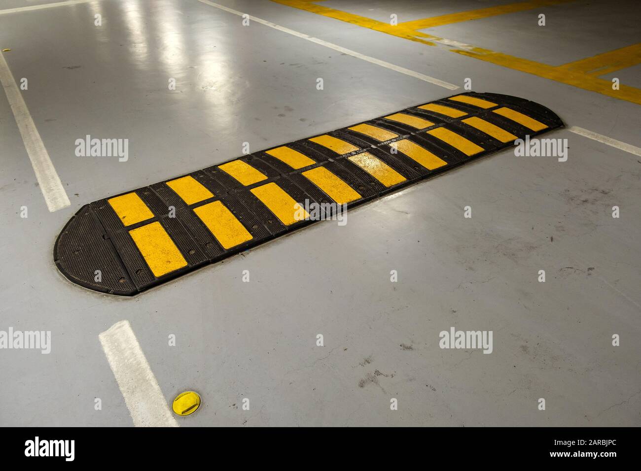 Striped black and yellow speed bump on a road. Stock Photo