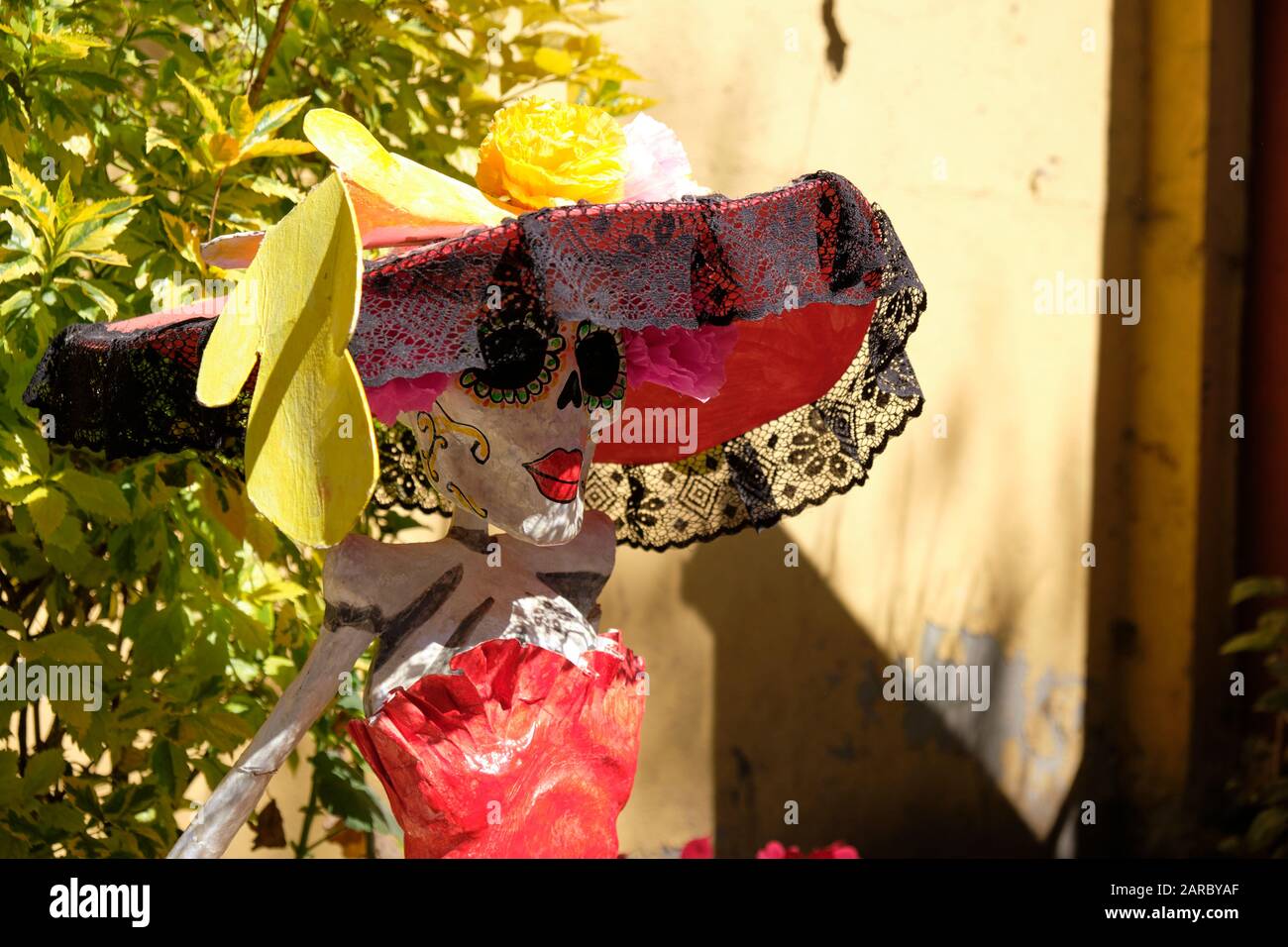 S traditional La Catrina mannequin with a large red hat, in a sunny courtyard Stock Photo