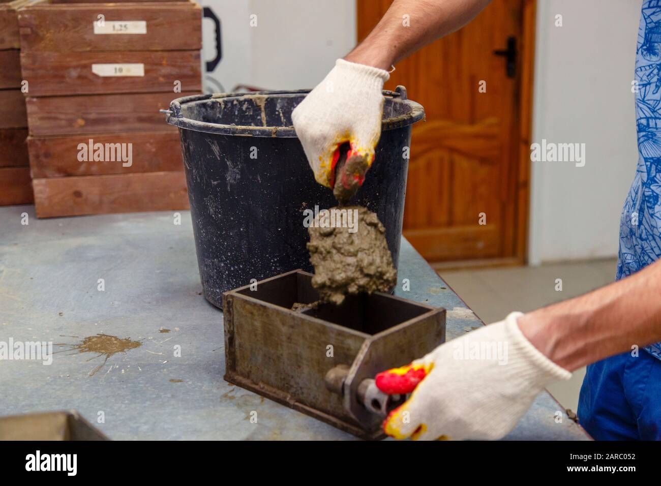 A member of the construction of the laboratory takes a sample of concrete. He loads the concrete into a special mold with a trowel. The result is a cu Stock Photo