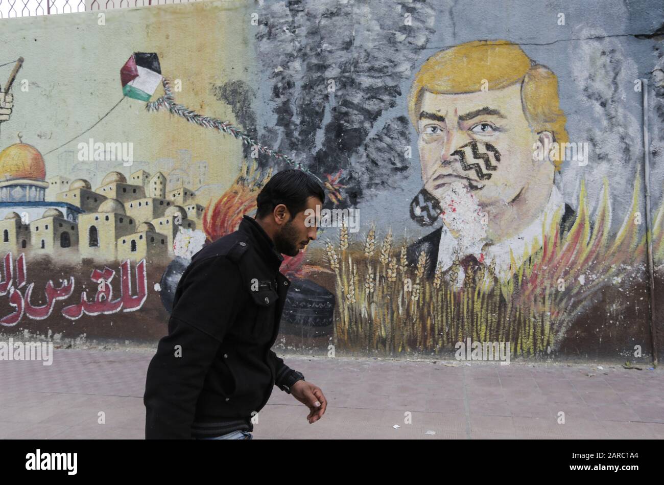 January 27, 2020, Gaza City, The Gaza Strip, Palestine: A Palestinian walks past a drawing of a wall drawn by Palestinian protesters showing the United States Donald J. Trump with a fingerprint on his face in the streets of Gaza City, Gaza Strip, on January 27, 2020 in Gaza City. - Palestinian Prime Minister Muhammad Shtayeh today called on international powers to boycott an American peace plan they see as biased towards Israel, as Israeli Prime Minister Benjamin Netanyahu and his political rival Benny Gantz are scheduled to meet with Donald Trump in Washington, and the American President is e Stock Photo
