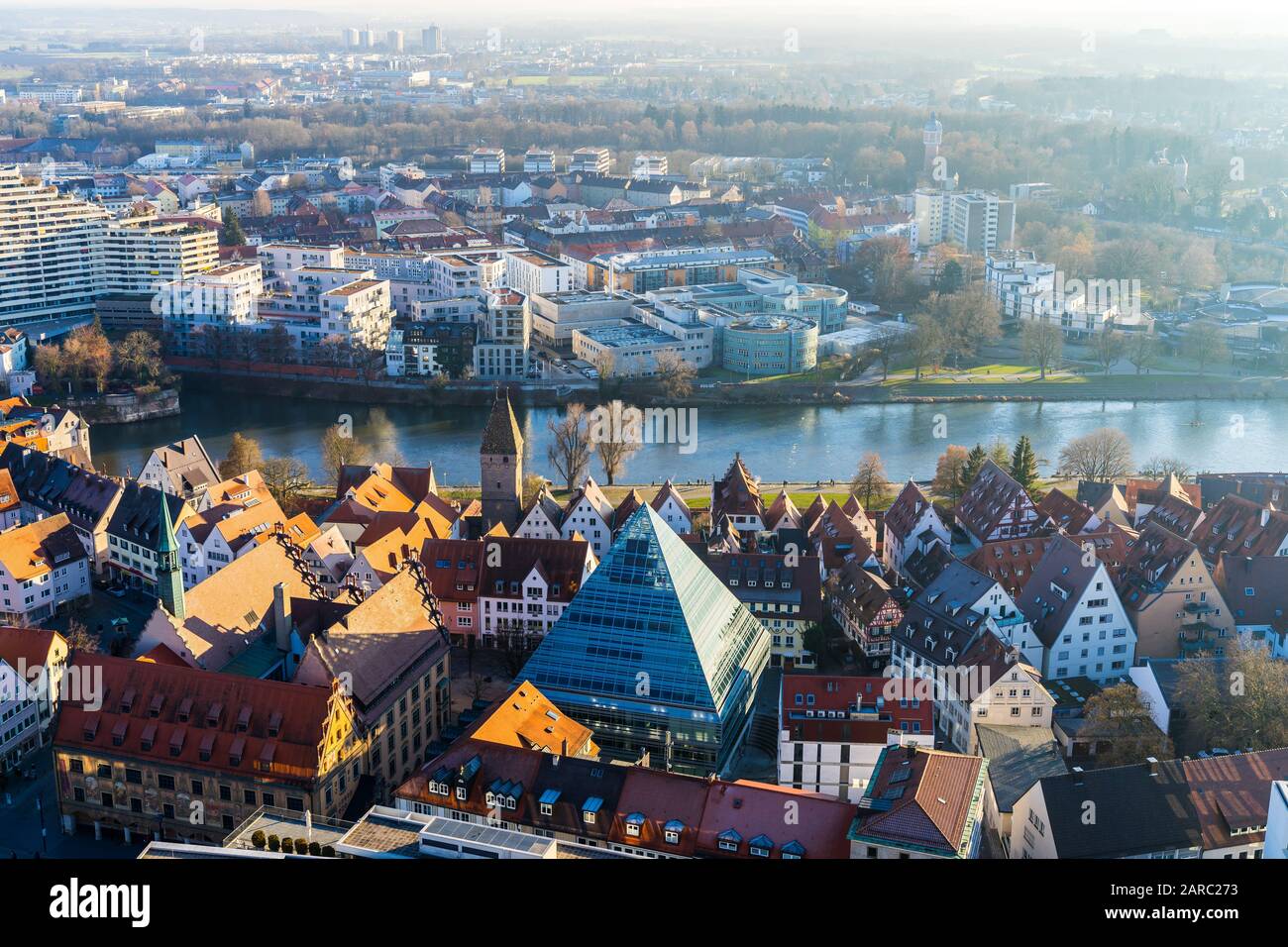 Ulm, Germany, December 29, 2019, Beautiful aerial view over roofs of old town houses and modern glass pyramid public library building next to danube r Stock Photo