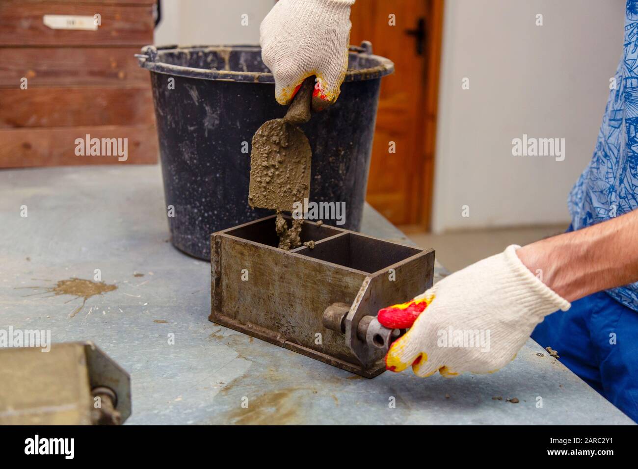A member of the construction of the laboratory takes a sample of concrete. He loads the concrete into a special mold with a trowel. The result is a cu Stock Photo