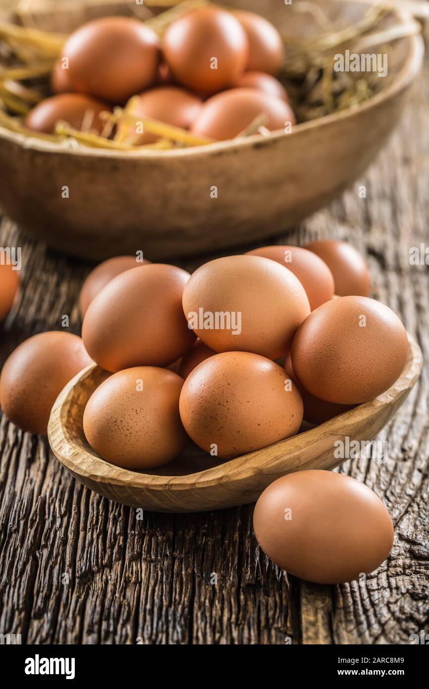 Fresh raw eggs in wooden bowl on rustic wooden table Stock Photo