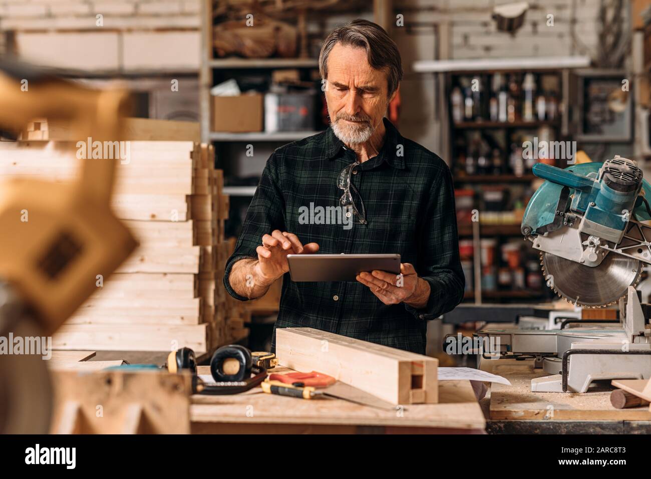 Senior carpenter using a digital tablet in his workshop Stock Photo