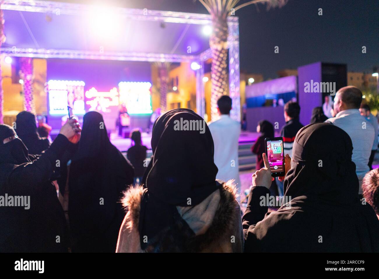 Women in Saudi Arabia filming an outdoor concert at night on their mobile phones in Riyadh at the Riyadh Season festival event Stock Photo