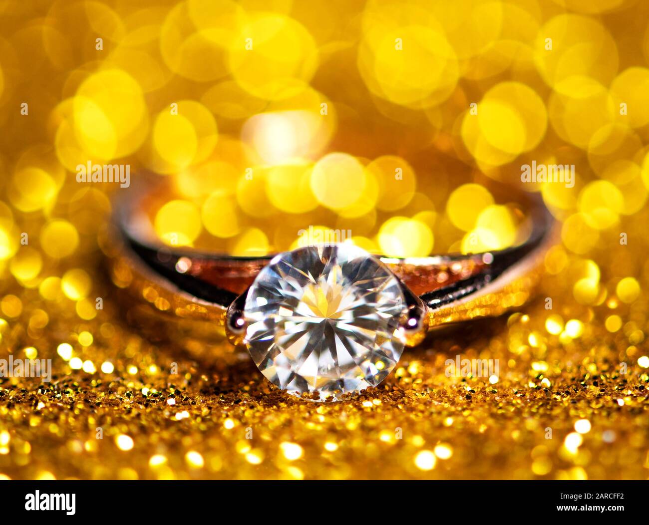 Wedding ring on gold glitter background. Selective focus Stock Photo