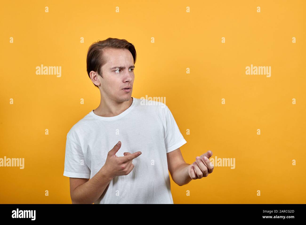 Young man looks away in surprise and raises his hands. Stock Photo