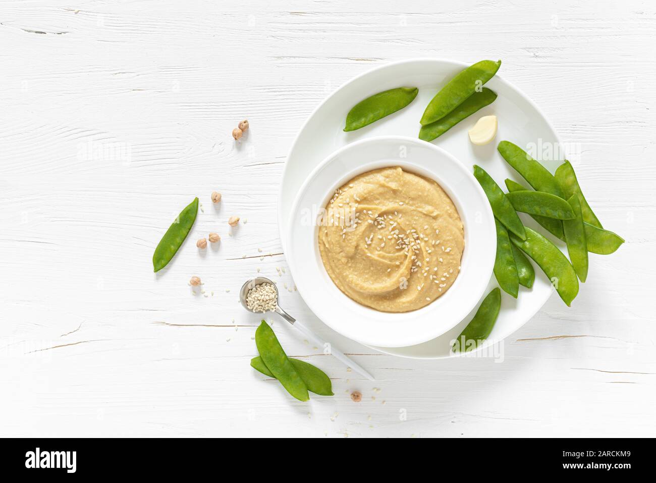 Homemade chickpea hummus served with green peas, healthy vegetarian