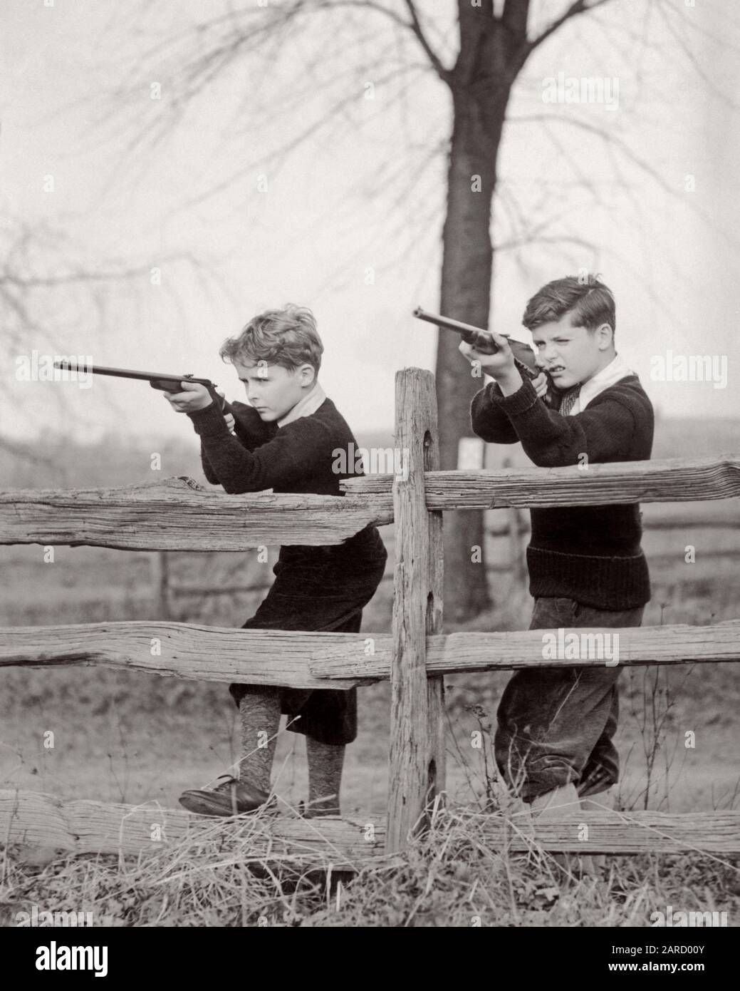 1930s TWO BOYS STANDING AT WOODEN SPLIT RAIL FENCE AIMING BOYS’ 22 CALIBER RIFLES WEARING PLUS FOURS AND SWEATERS - a3258 HAR001 HARS SPLIT RAIL SKILL ADVENTURE AND POWERFUL RECREATION FALL SEASON FIRING SIBLING SWEATERS FRIENDLY RIFLES STYLISH 22 FOURS PLUS AIMING CAL CALIBER COOPERATION FIREARM FIREARMS JUVENILES PRE-TEEN PRE-TEEN BOY SHARPSHOOTER TOGETHERNESS AUTUMNAL BLACK AND WHITE CAUCASIAN ETHNICITY FALL FOLIAGE HAR001 MARKSMAN OLD FASHIONED Stock Photo