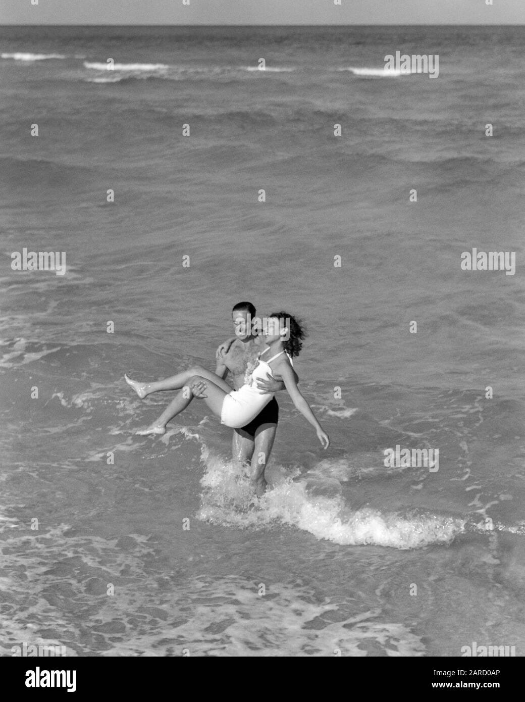 1930s 1940s LAUGHING SMILING VACATION COUPLE WEARING BATHING SUITS PLAYING IN OCEAN SURF AT BEACH MAN CARRYING WOMAN FLORIDA USA - b7080 HAR001 HARS LIFTING TROPICAL YOUNG ADULT BALANCE COMIC TEAMWORK VACATION JOY LIFESTYLE OCEAN FEMALES MARRIED SPOUSE HUSBANDS HEALTHINESS UNITED STATES COPY SPACE FRIENDSHIP FULL-LENGTH LADIES PERSONS UNITED STATES OF AMERICA MALES SURF B&W PARTNER NORTH AMERICA NORTH AMERICAN TIME OFF SHORE HUMOROUS HAPPINESS LEISURE STRENGTH TRIP GETAWAY EXCITEMENT RECREATION COMICAL AT IN BEACHES HOLIDAYS CONNECTION CONCEPTUAL COMEDY SANDY STYLISH BATHING SUITS RELAXATION Stock Photo