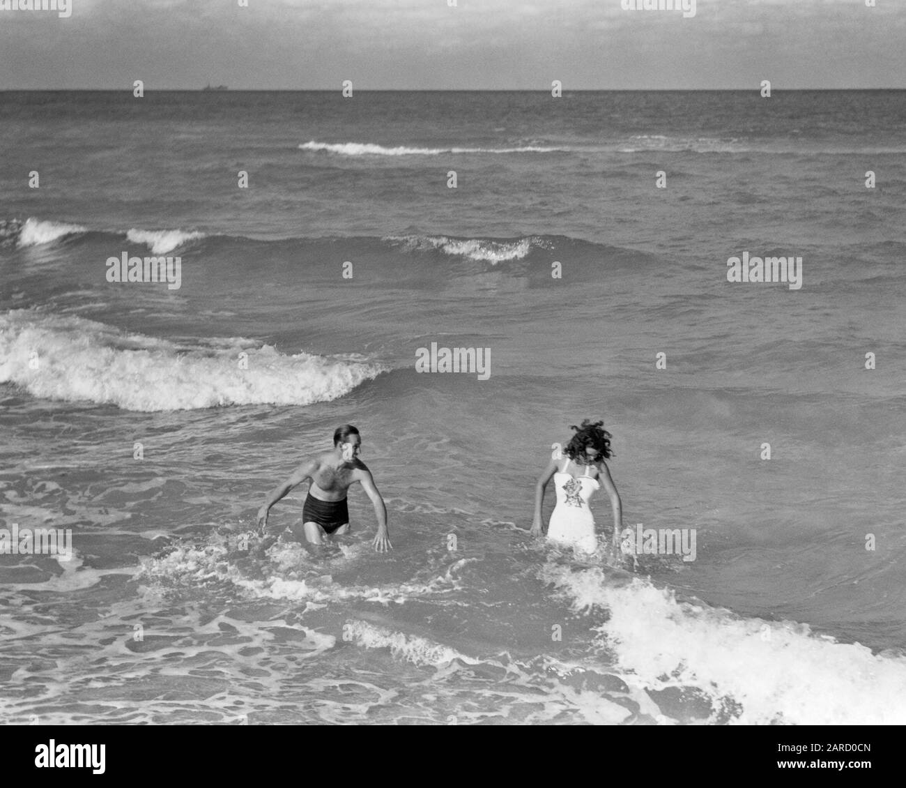 1930s 1940s VACATION COUPLE WEARING BATHING SUITS STANDING WALKING PLAYING IN OCEAN SURF AT BEACH TOGETHER FLORIDA USA - b7138 HAR001 HARS EXERCISING NOSTALGIC ACTIVE PAIR ROMANCE OLD TIME NOSTALGIA OLD FASHION 1 FITNESS SILLY TROPICAL HEALTHY BALANCE COMIC VACATION ATHLETE PLEASED JOY LIFESTYLE OCEAN FEMALES MARRIED SPOUSE HUSBANDS HEALTHINESS ATHLETICS UNITED STATES COPY SPACE FRIENDSHIP FULL-LENGTH LADIES PERSONS UNITED STATES OF AMERICA MALES ATHLETIC SURF B&W PARTNER NORTH AMERICA FREEDOM NORTH AMERICAN TIME OFF ACTIVITY HUMOROUS HAPPINESS PHYSICAL CHEERFUL HIGH ANGLE LEISURE STRENGTH Stock Photo