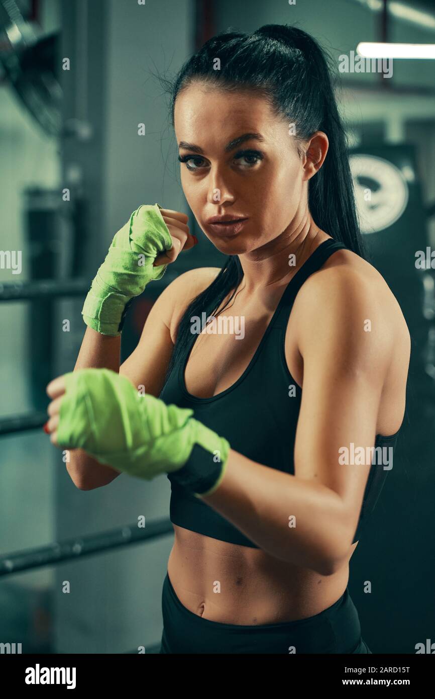 Athletic woman standing prepared for fight with boxing bandages on hands during box training Stock Photo