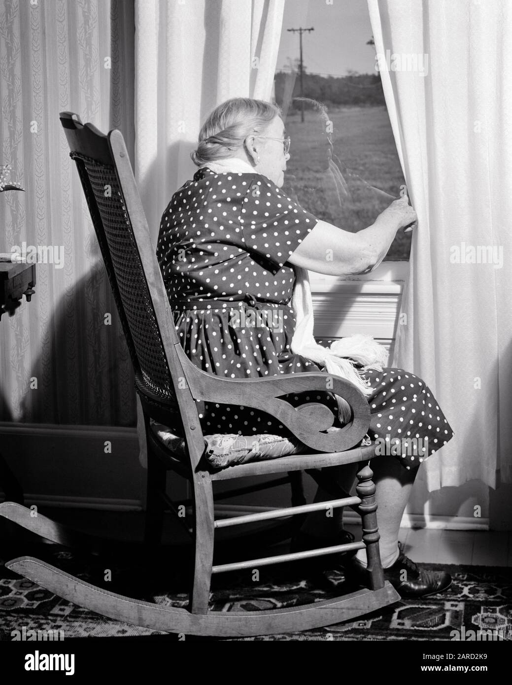 1960s SENIOR WOMAN SITTING IN ROCKING CHAIR BY WINDOW LOOKING OUT FOR ANTICIPATED VISITOR OR NOSEY BIDDY SPYING ON NEIGHBORS - s14450 CRS001 HARS ROCKING INFORMATION LIFESTYLE ELDER FEMALES MOODY RURAL HOME LIFE COPY SPACE FULL-LENGTH LADIES PERSONS CARING ENTERTAINMENT SENIOR ADULT TROUBLED B&W SADNESS SENIOR WOMAN NEIGHBORS OLD AGE OLDSTERS OLDSTER DISCOVERY HOPE AGING RECREATION BY IN ON ANTICIPATION AUTHORITY MOOD SPYING ELDERS CONCEPTUAL GLUM POLKA DOT VISITOR LONELINESS NOSEY OR BIDDY ELDERLY WOMAN MISERABLE BLACK AND WHITE CAUCASIAN ETHNICITY OLD FASHIONED Stock Photo