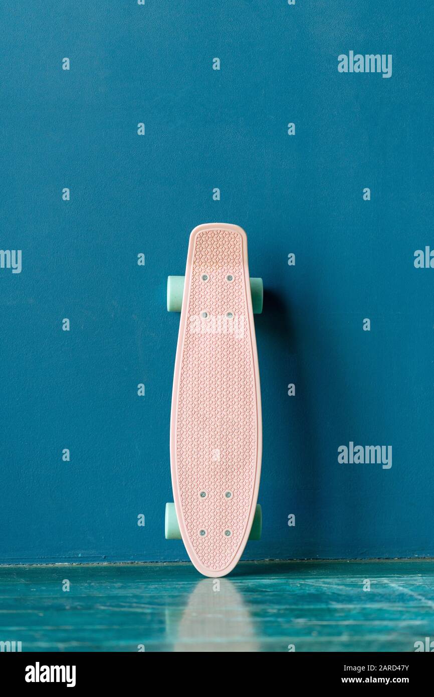 Plastic skateboard standing near a blue wall Stock Photo