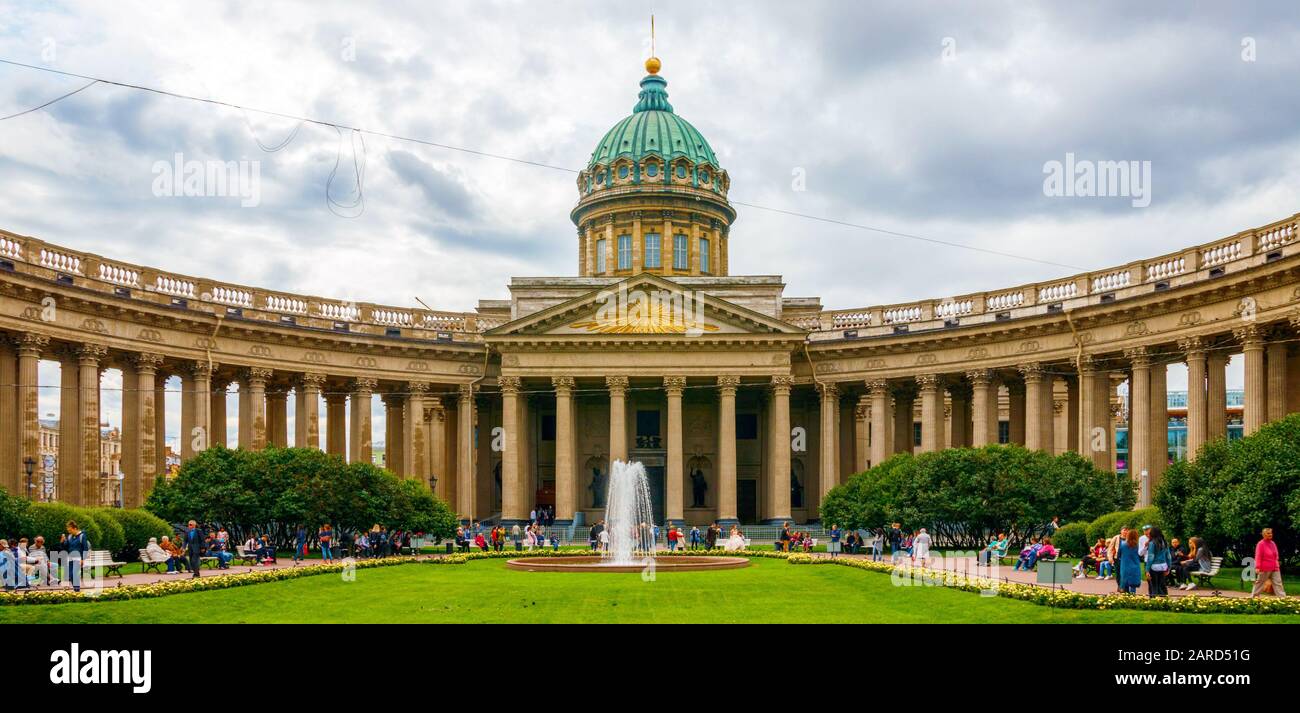 Panoramic view of the Kazanskiy Kafedralniy Sobor (Kazan Cathedral) and unidentified people in the park under a cloudy sky. Saint Petersburg, Russia. Stock Photo