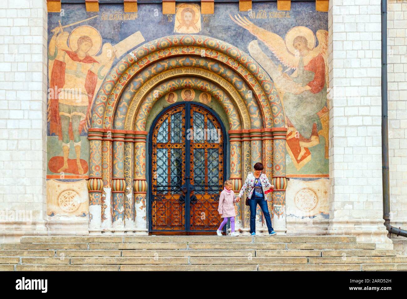 Unidentified sightseeing tourists at the beautifully painted south entrance of the Dormition Cathedral, part of the Moscow Kremlin. Russia. Stock Photo
