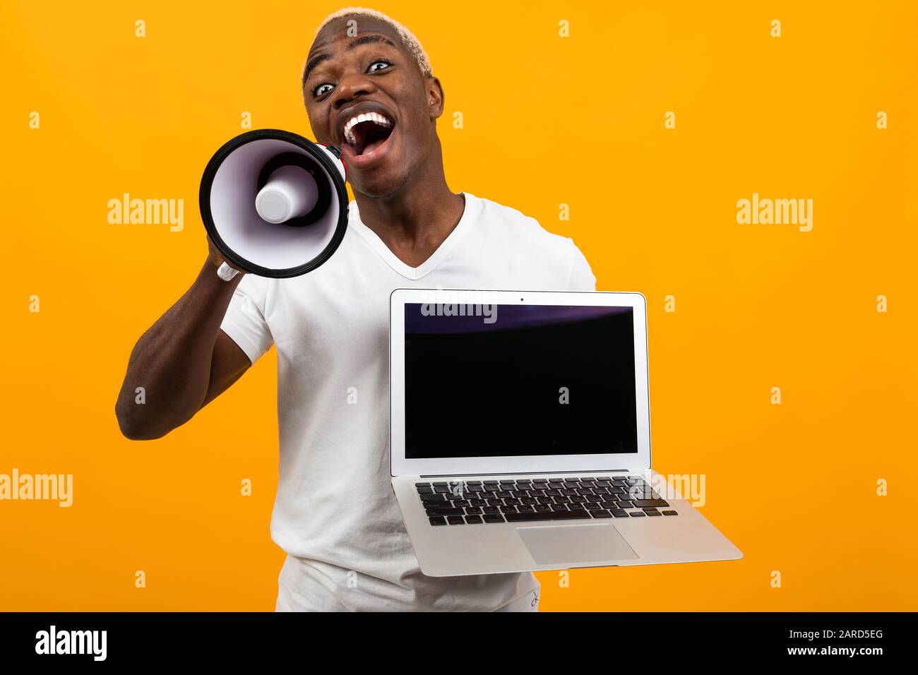 Download African Black Man With White Hair With A Megaphone And Laptop With A Mockup On A Yellow Studio Background Stock Photo Alamy
