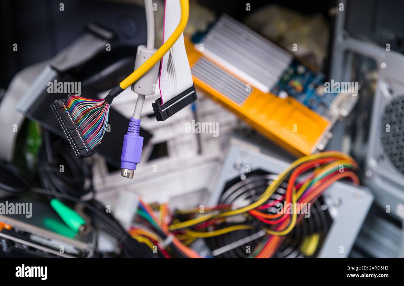 Obsolete computer spare parts. E-waste dump. Hanging colored multi wire ribbon cables with connectors. Ecological footprint and sustainable developmen Stock Photo