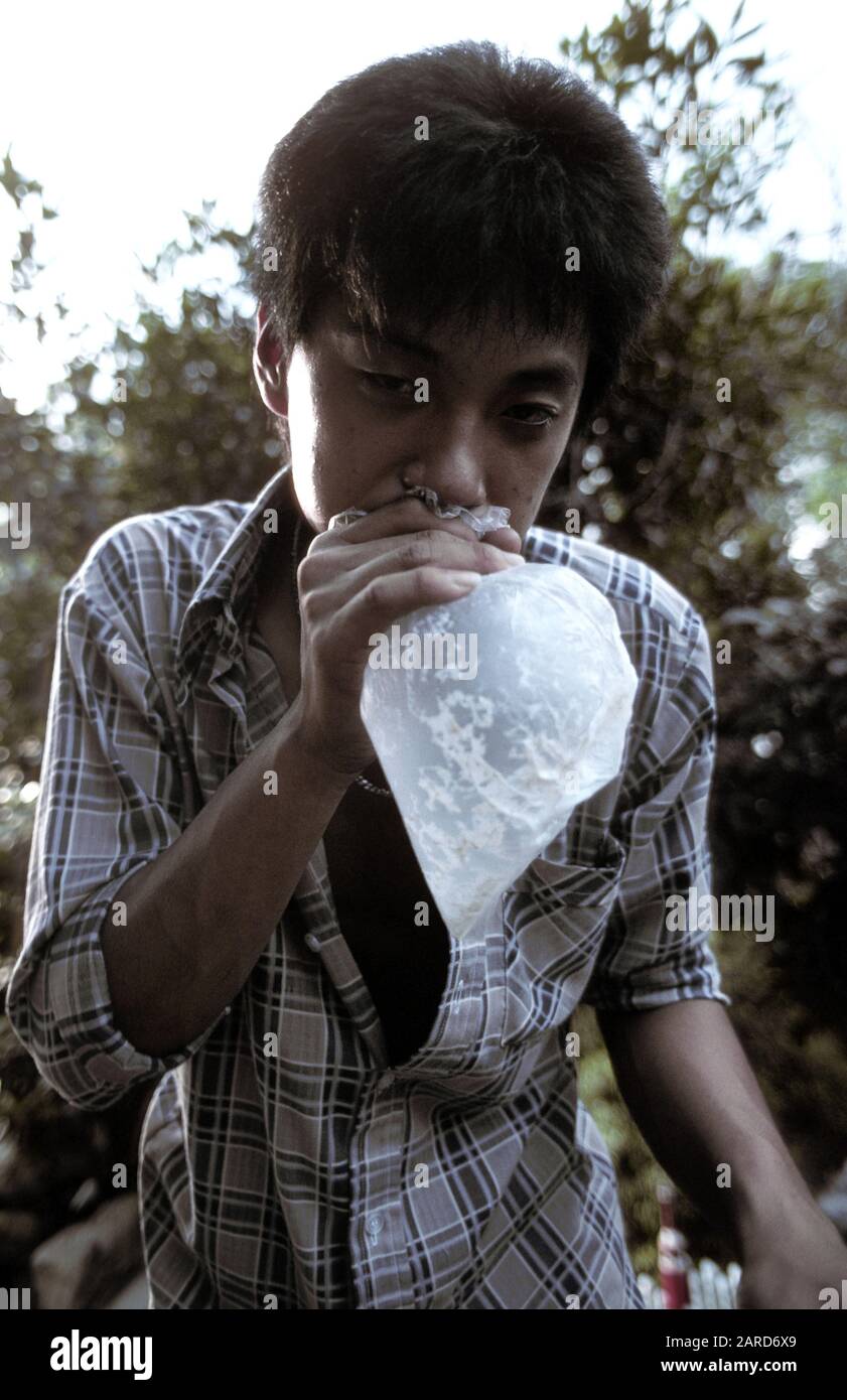 YOUNG MAN IN SINGAPORE GLUE SNIFFING. ALSO KNOWN AS BAGGING, GLADING, DUSTING OR HUFFING. Stock Photo