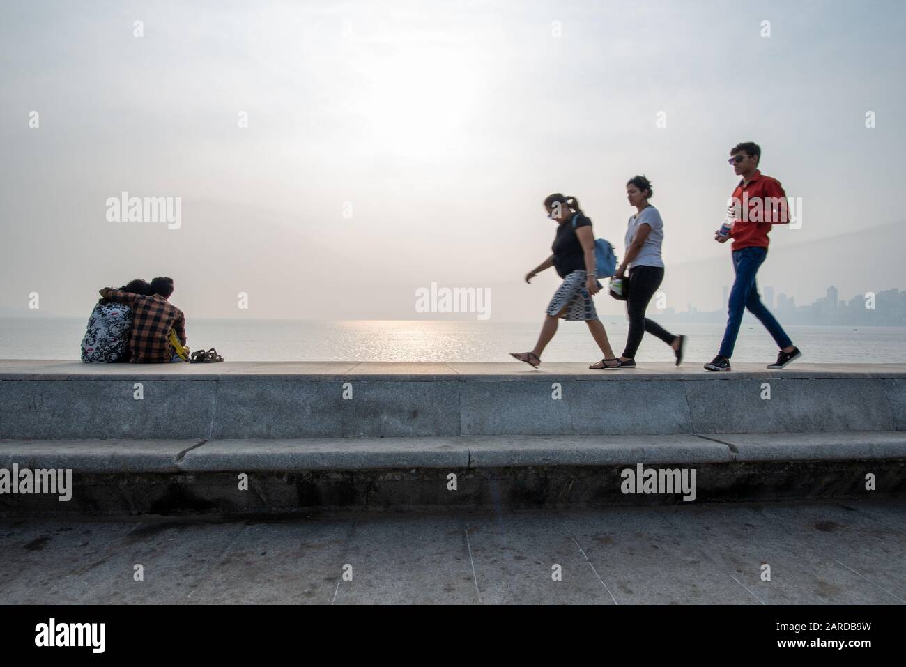 Mumbai, India - December 15, 2017: Lovers on Marine Drive with three passersby, taken at the end of the afternoon Stock Photo