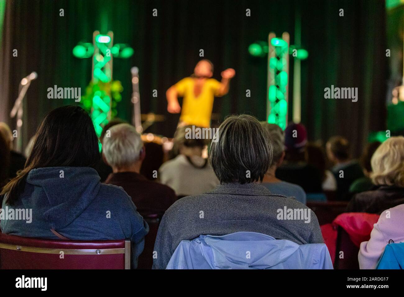 Rear View Of Audience Enjoying And Listening Male Artist Telling Story On Stage Against Curtain In Illuminated Auditorium At Night Stock Photo Alamy