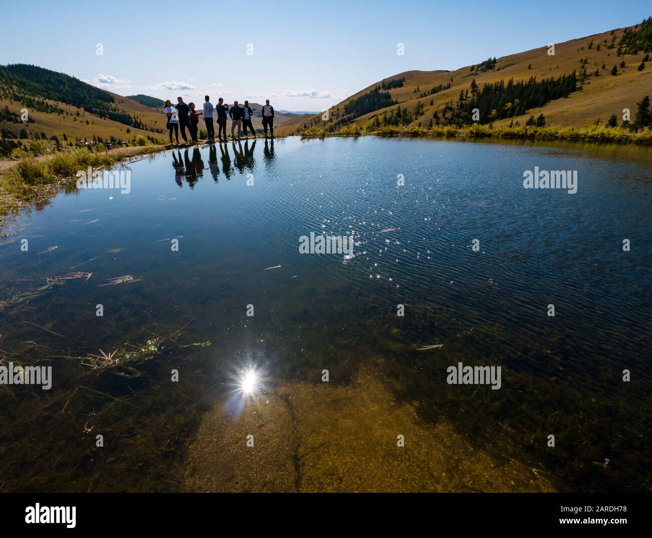 Visitors standong on edge of pond, Manzushir Khiid or Manjusri Monastery, Bodg Khan Mountains, Mongolia Stock Photo