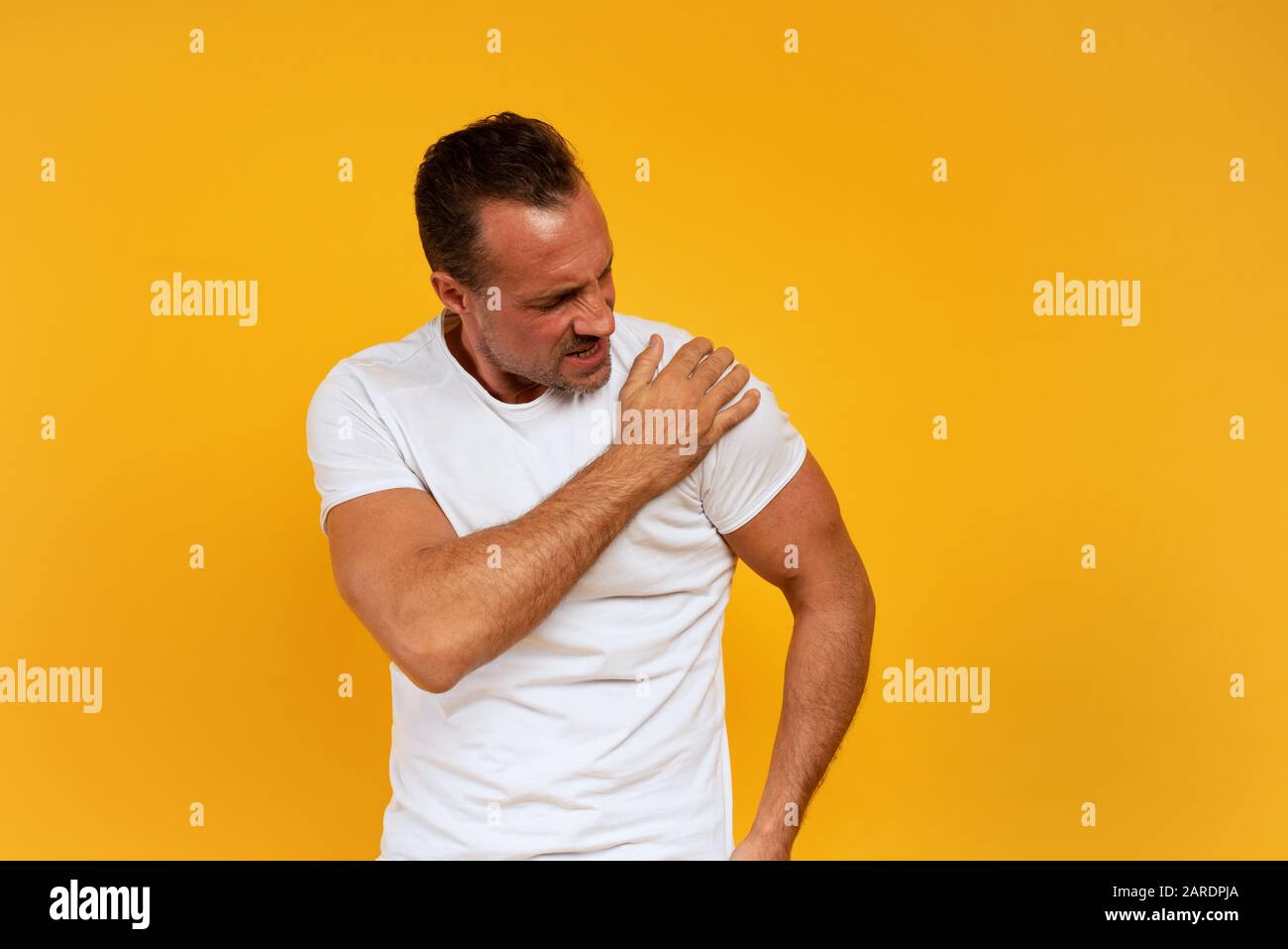 Aching man with back pain. Yellow background Stock Photo