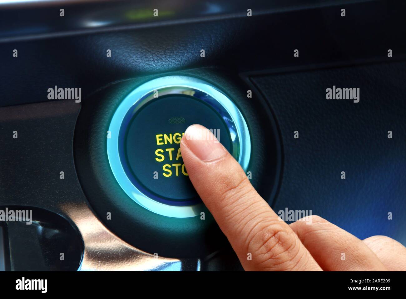 Finger pressing the start or stop engine button in close up. Stock Photo