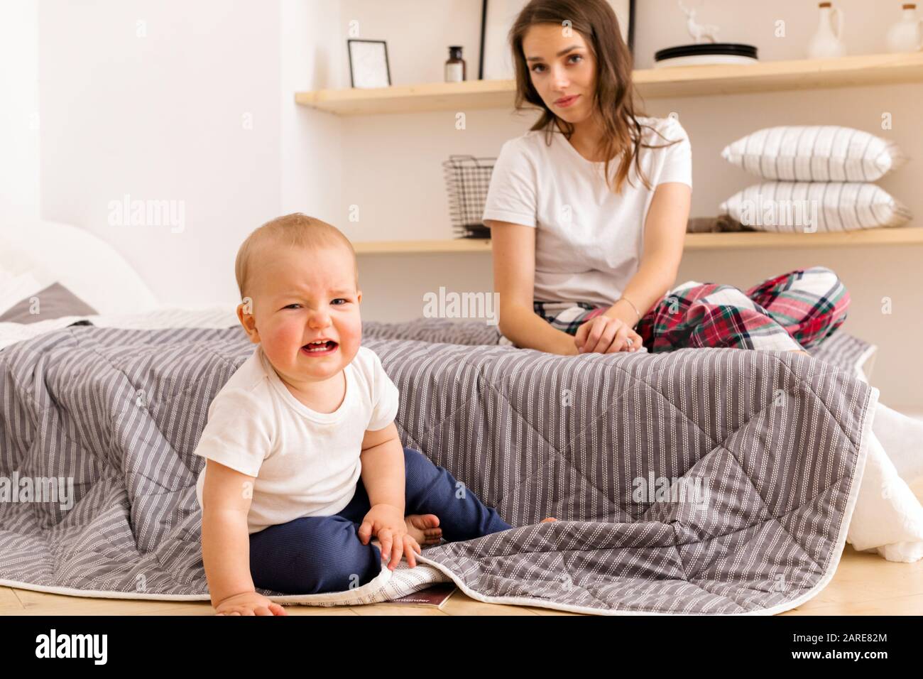 Mother with crying toddler in bedroom Stock Photo
