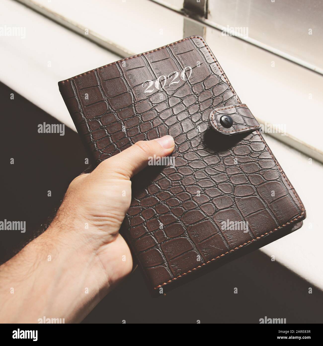 Closeup shot of a hand holding a 2020 planner with leather cover Stock Photo