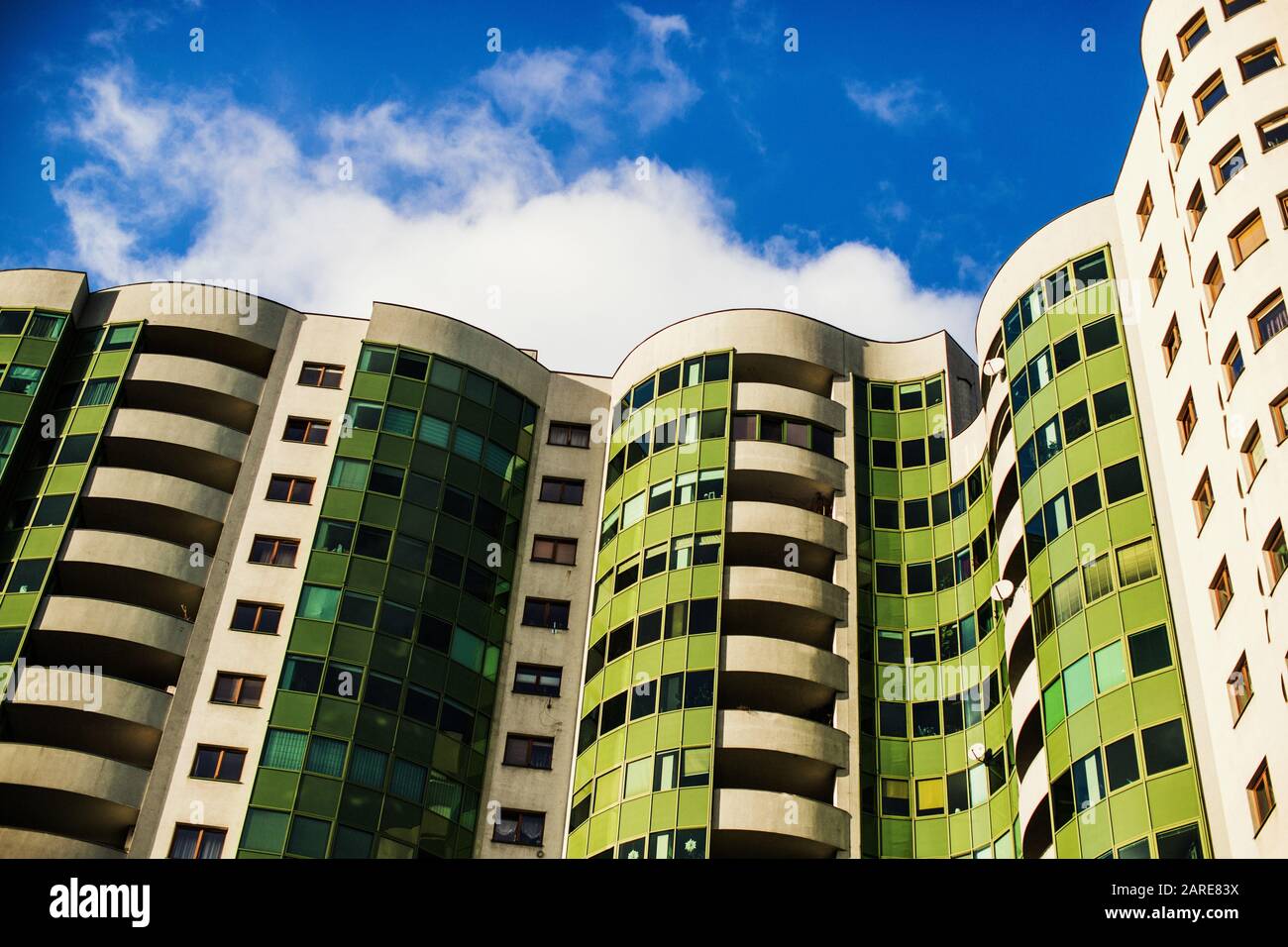 Curvy modern green apartment building under the sunlight and a blue sky