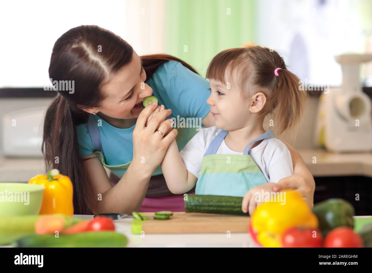 Child girl and her mother cooking in kitchen Stock Photo