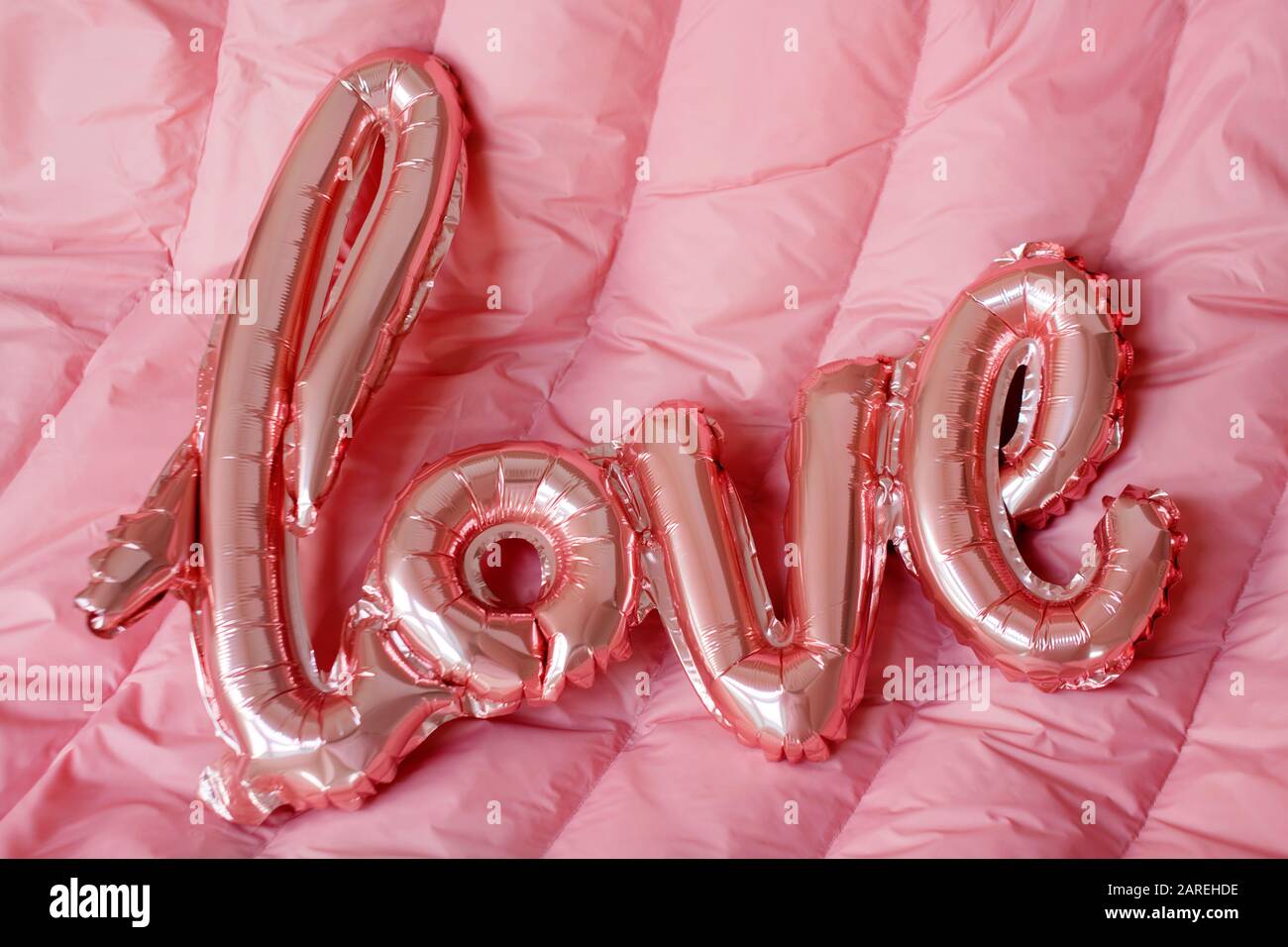 Love word from pink inflatable balloon on pink background. The concept of  romance, Valentine's Day. Love rose gold foil balloon Stock Photo - Alamy