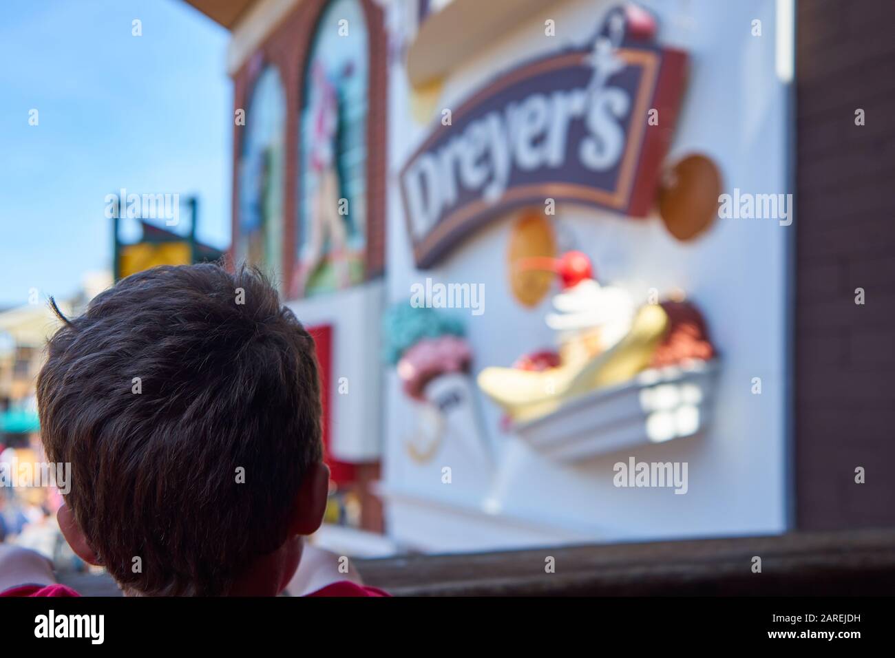 The back of head of boy looking earnestly at Dreyer's ice cream store sign at Pier 39 in San Francisco California on a sunny and pleasant day. Stock Photo