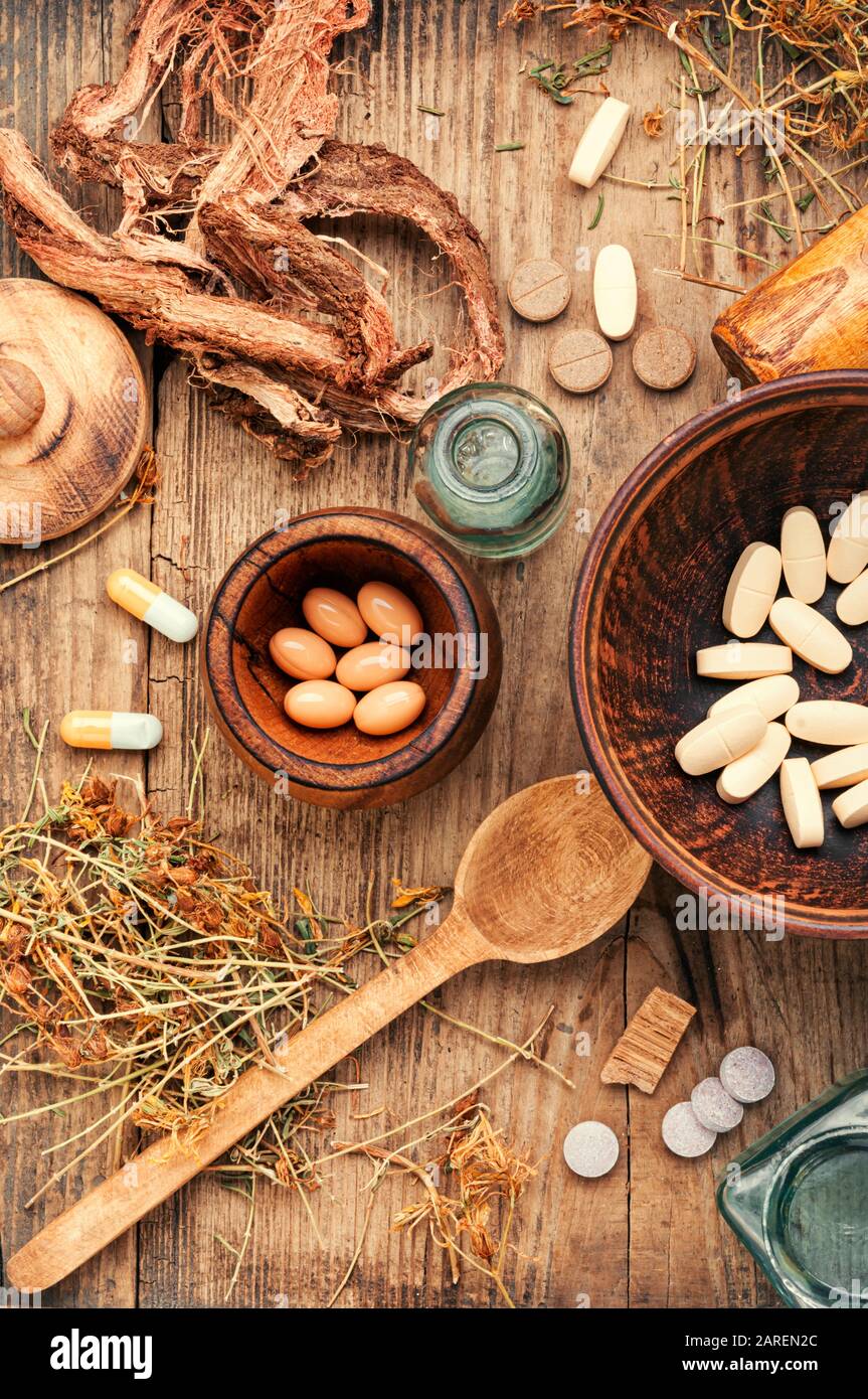 Herbal medical pills with healing plant on wooden table.Alternative medicine tablets Stock Photo