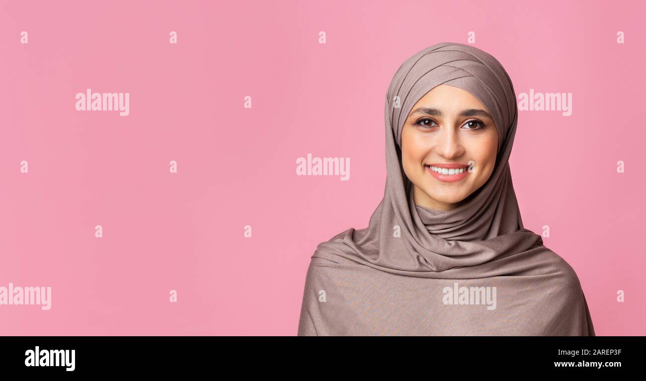 Portrait of smiling islamic woman in hijab over pink background Stock ...
