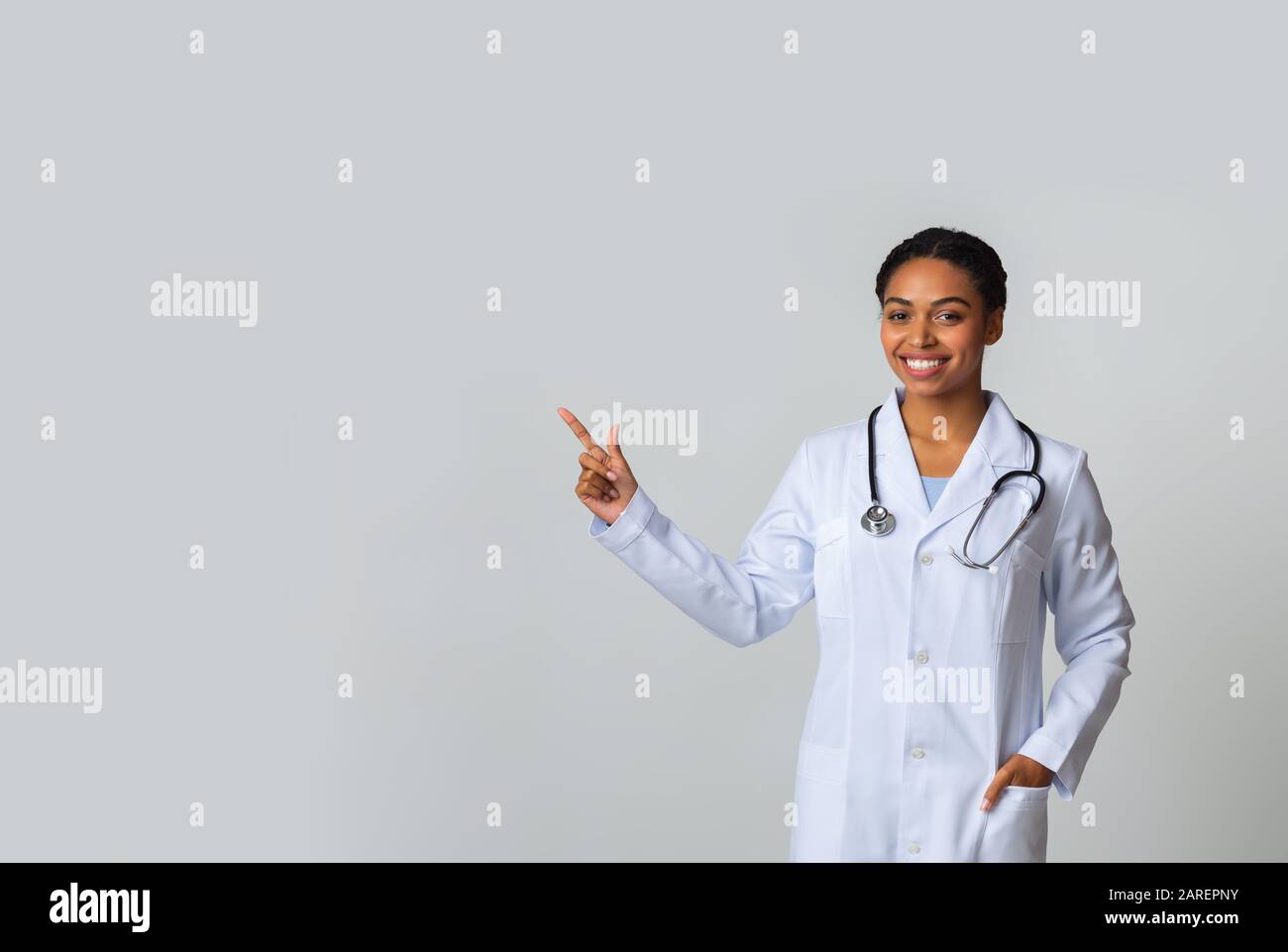 Young black female doctor pointing at copy space on light background Stock Photo