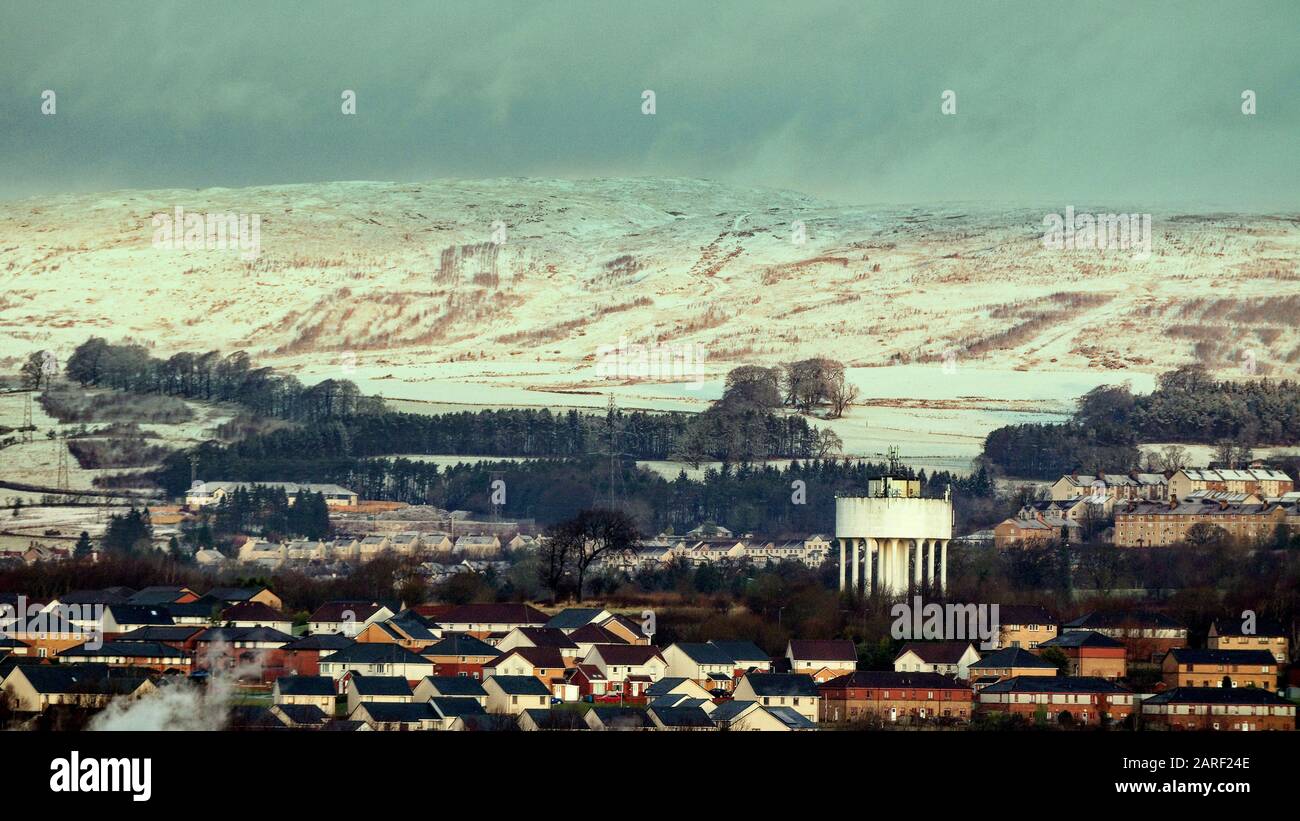 Glasgow, Scotland, UK, 28th January, 2020: UK Weather: Weather warnings for snow saw the first falls hit the city resulting in white hills in up-lying areas.The drumchapel housing estate at the foot of the snow covered kilpatrick hills with its famous water tower. Gerard Ferry/ Alamy Live News Stock Photo