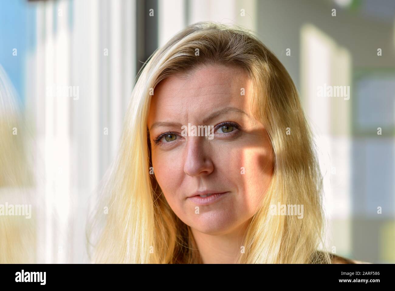 Attractive blond woman standing daydreaming looking to the camera Stock Photo