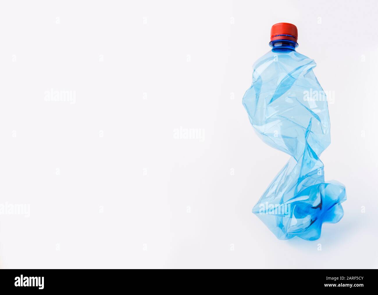 Crumpled or squashed blue plastic bottle isolated on white Stock Photo