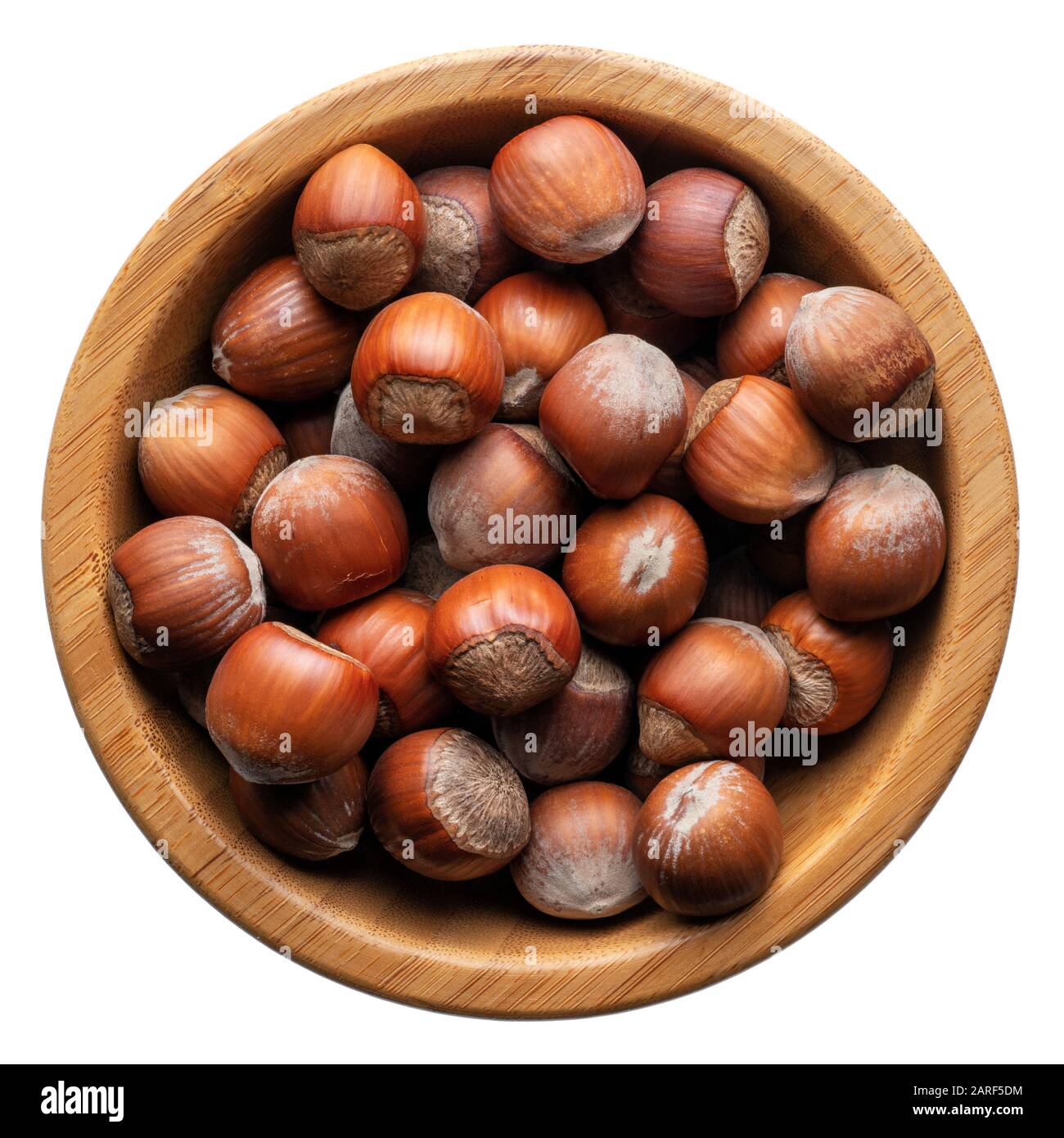Food and drinks: group of unpeeled hazelnuts in a round wooden bowl, isolated on white background Stock Photo