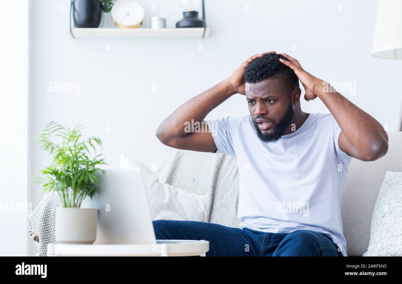 Shocked african guy looking at broken laptop Stock Photo