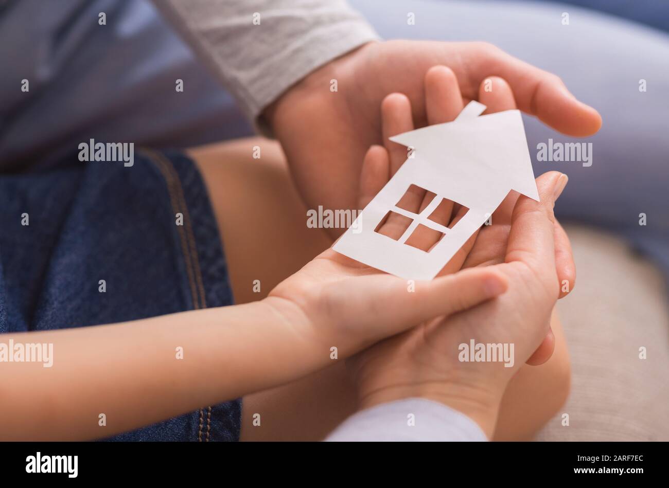 Closeup of family of three holding paper house in hands Stock Photo