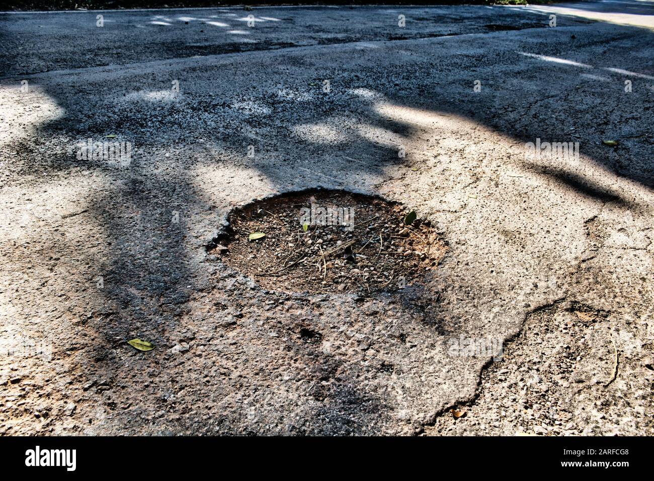 This unique photo shows a pothole in a gray paved road. As so often symbolizes caution and danger on the streets of thailand Stock Photo